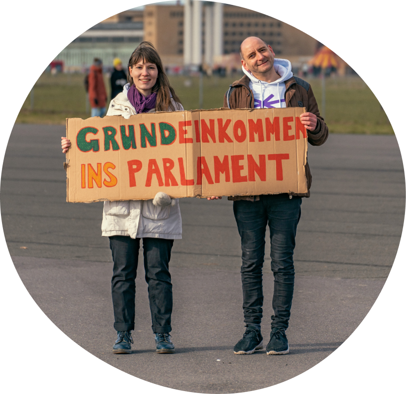 Menschen aus der Expedition mit einem Plakat mit der Aufschrift "Grundeinkommen ins Parlament"